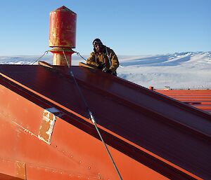 Expeditioner on the roof of the red sleeping/medical quarters checking all loose guy lines on cowls