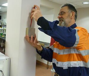 An electrician calibrating the thermostat in the Living Quarters