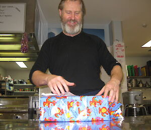 An expeditioner smiling when about to open his gift wrapped present