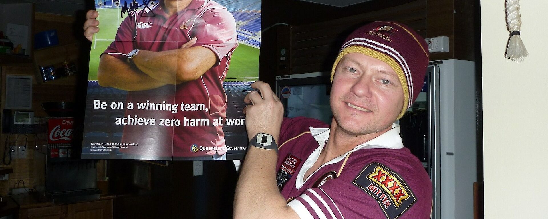 An expeditioner holding a Queensland WorkCover poster signed safety ambassador Mal meninga
