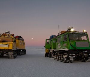 Two vehicles on sea ice with pink sky in background