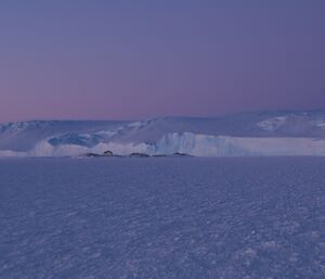 Some small rocky islands very close to the Antarctic plateau and a pinky mauve sky
