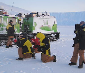 Expeditioners setting up their cameral equipment close to the parked Hägglunds