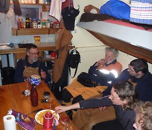 Five expeditioners in a field hut relaxing after being with the penguins during the day