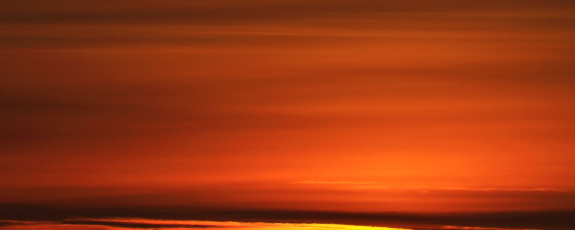 The rising sun just above the horizon with the sky lit up
