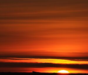 The rising sun just above the horizon with the sky lit up