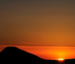 Sunrise on 20th July with the rising sun to the right of the conical shaped Welch Island