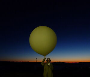 Vicki with the sonde in her left hand and the balloon held aloft with her right hand