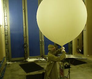 Tying off the balloon after filling it with hydrogen in the Balloon Shed