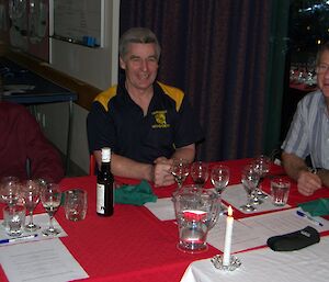 Three people sitting talking at a dinner table with wine tasting glasses in front of them