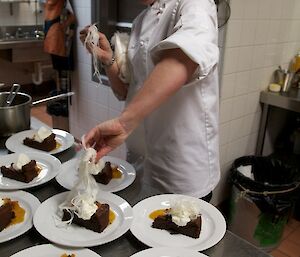 Chef putting white fairy floss on top of individual servings of cake