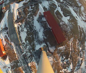 Looking down out of the rear hatch of the wind turbine showing some different coloured buildings, site service lines and Mawson rock