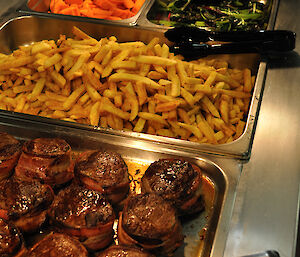 Filet mignon, chips, carrots and greens in a bain marie