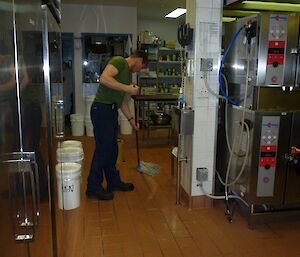 An expeditioner mopping the kitchen floor after the birthday party