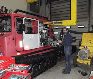 An expeditioner is refitting the engine with the engine lifting frame. A yellow heater is on his right and a tool box in the left forground of the photo