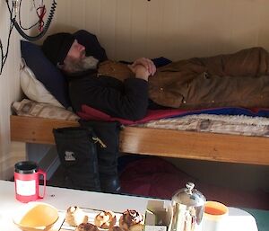 Person lying on bed in a small hut