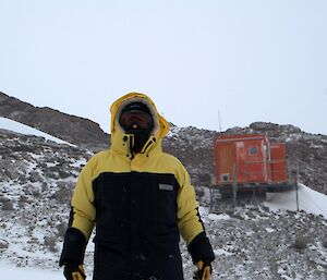 Person in cold weather clothing in front of a field hut