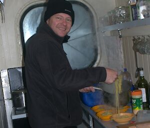 Person in small kitchen serving bowls of soup