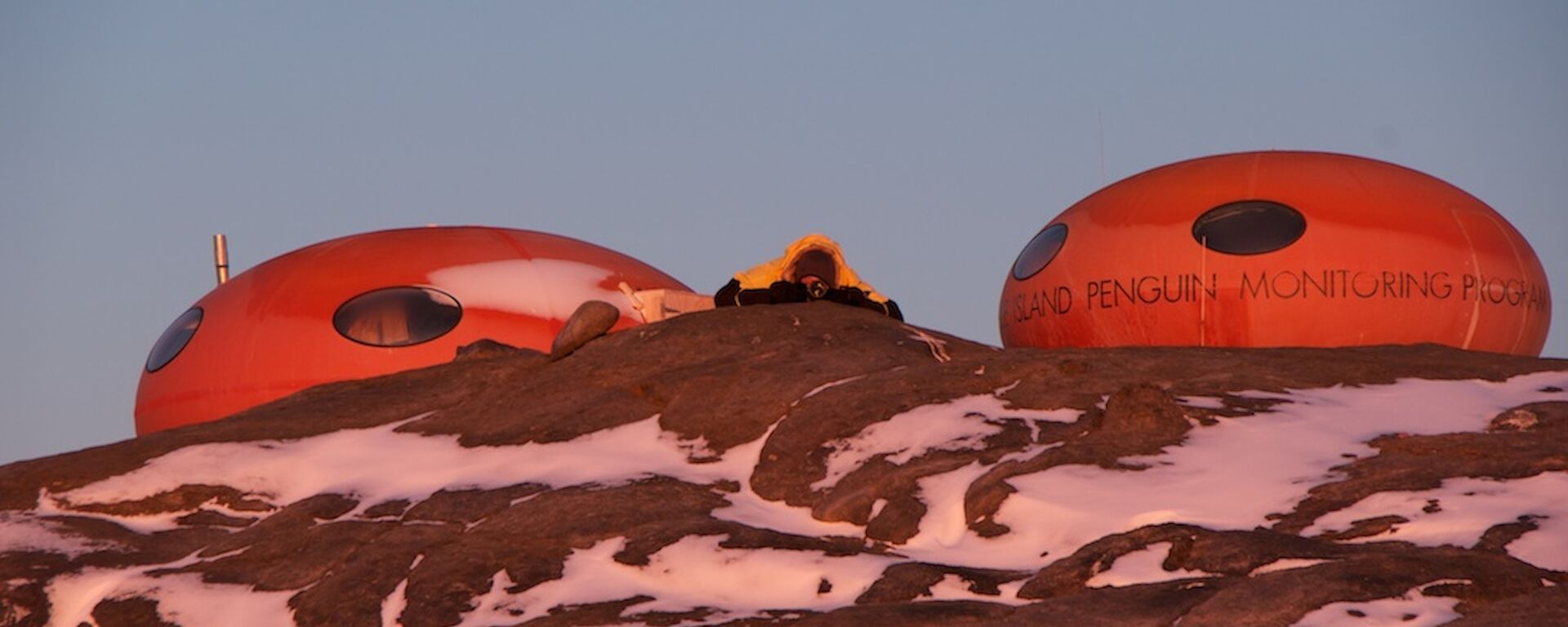 Two oval shaped huts with a person on the ground between them