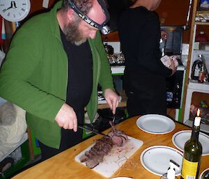 Person preparping food at a table inside a hut