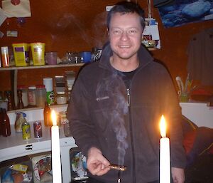 Person lighting two candles at a dinner table