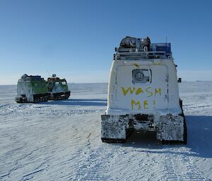The green and yellow Hägglunds on the sea-ice. There is a smiley face on the back cab window and the words ‘wash me’ in the snow on the back of the yellow Hägglunds.