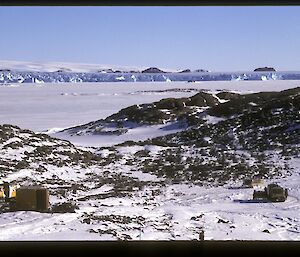 General view of the area around the hut in 1997. Note the exposed rocks which are now deeply covered with snow. Behind the island is sea-ice, the Taylor Glacier and the Antarctic icecap.
