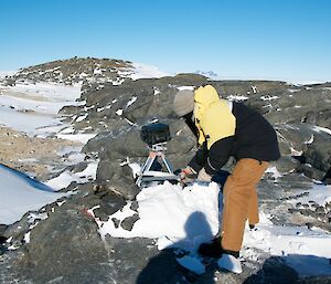 An expeditioner delicately removing snow from the solar panel with his snow axe