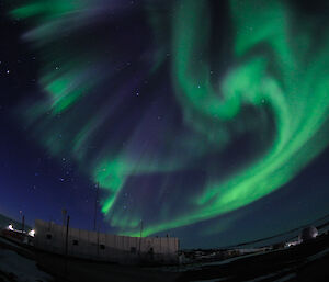 Green curtains of light in the sky and the white Aeronomy Building visible