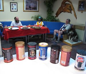 Row of beer kits on table with people in background