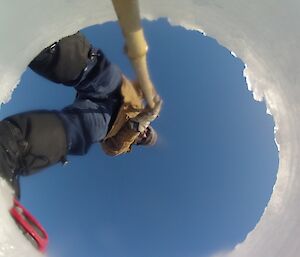 Robert inserting his camera attached to a bamboo cane down the hole drilled through the sea ice