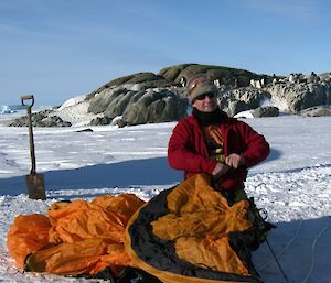 An expeditoner in the process of erecting his tent on the snow