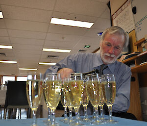 The Station Leader pouring champagne into 15 flutes