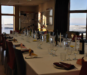The dinner table set up with individual places and the view through the windows showing sea-ice and icebergs