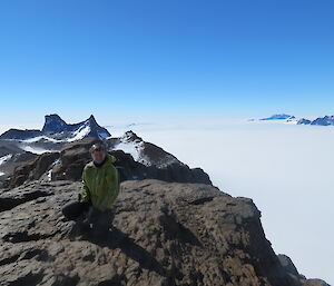 An expeditioner on Mt Elliott with 2 mountain ranges rising from the ice plateau to her left