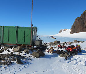 Looking east at the Green Rum Doodle field hut with quad bikes close by and mountains on the right