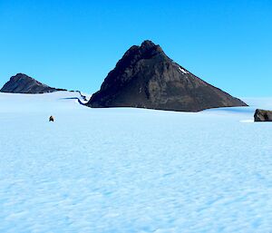 A quad and its rider appear tiny in relation to teh vastness of the plateau and 2 mountains