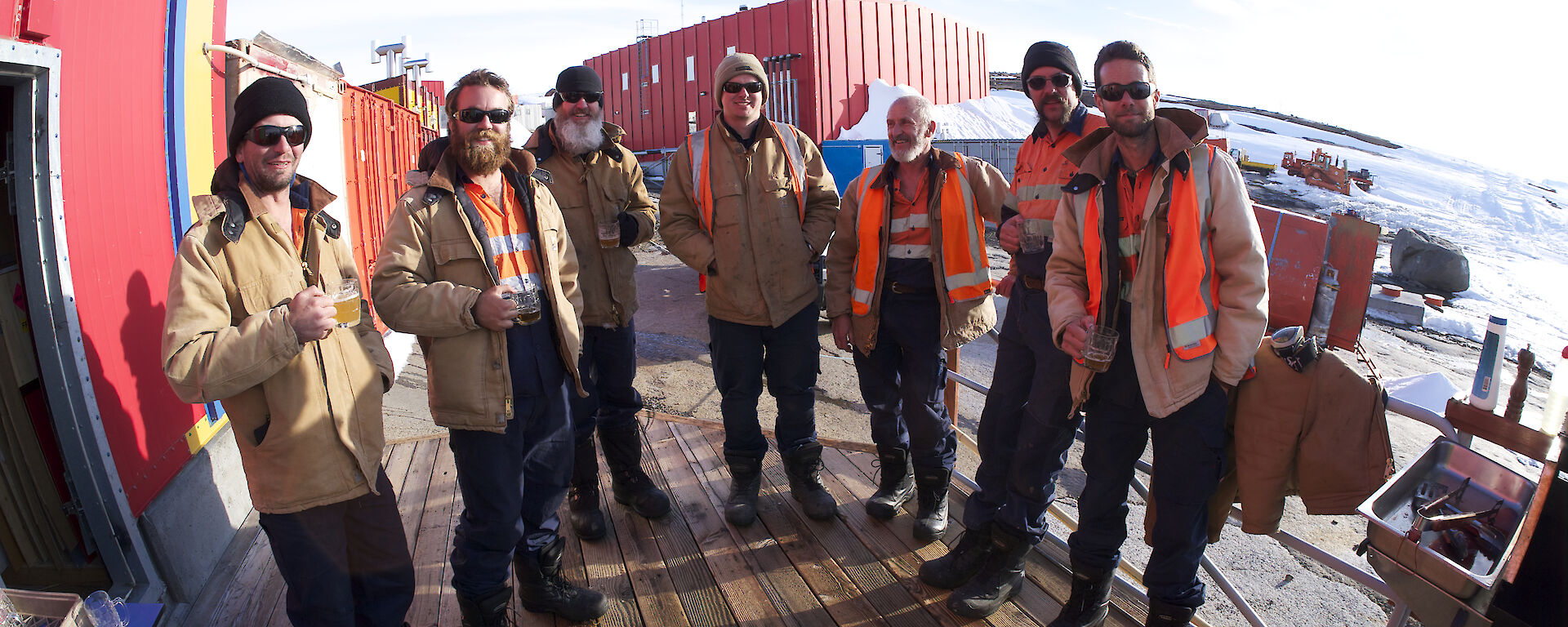 Seven expeditioners stadning on the verandah of the Rosella Building at the barbecue