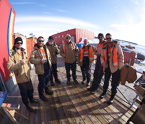 Seven expeditioners stadning on the verandah of the Rosella Building at the barbecue