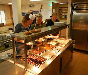 Three expeditioners at the Bain Marie holding the 3 Asian dishes and 2 types of rice