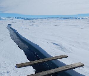 An open tide crack with planks set-up to cross