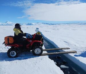 Quad bike crossing wooden plank over tide crack