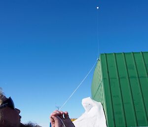 Expeditioner moving balloon above green store on string