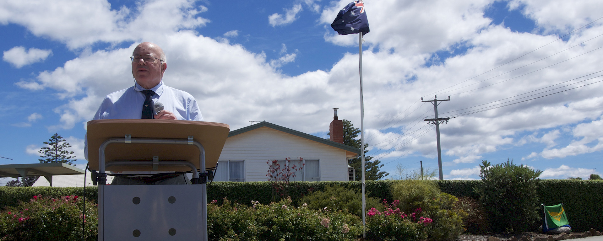 Bob Dingle’s friend and polar historian, Herbert Dartnall reads a speech at Bob’s memorial. The covered plaque on a granite boulder is behind, covered in an ANARE flag.