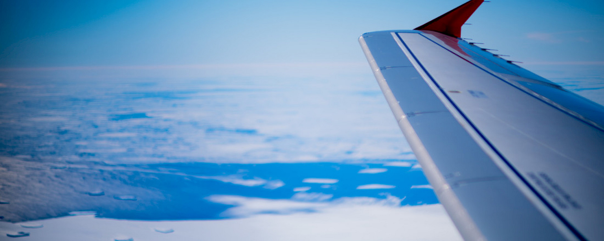 View out Airbus window of plane wing and white surface.