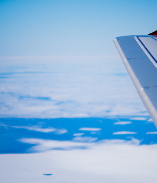 View out Airbus window of plane wing and white surface.