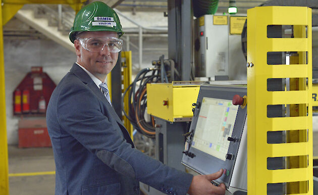 Man in hard hat about to hit button on panel