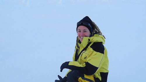Female on sea ice with penguins behind her