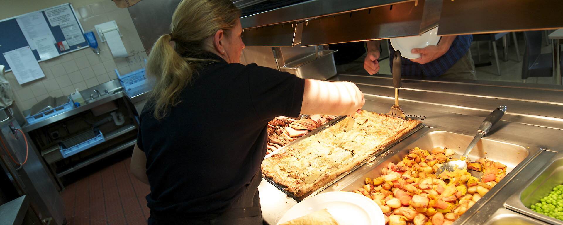 A chef at Casey filling the hot food servery.