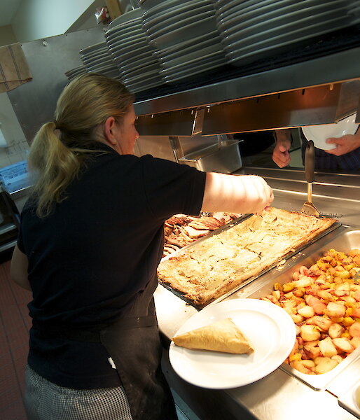 A chef at Casey filling the hot food servery.